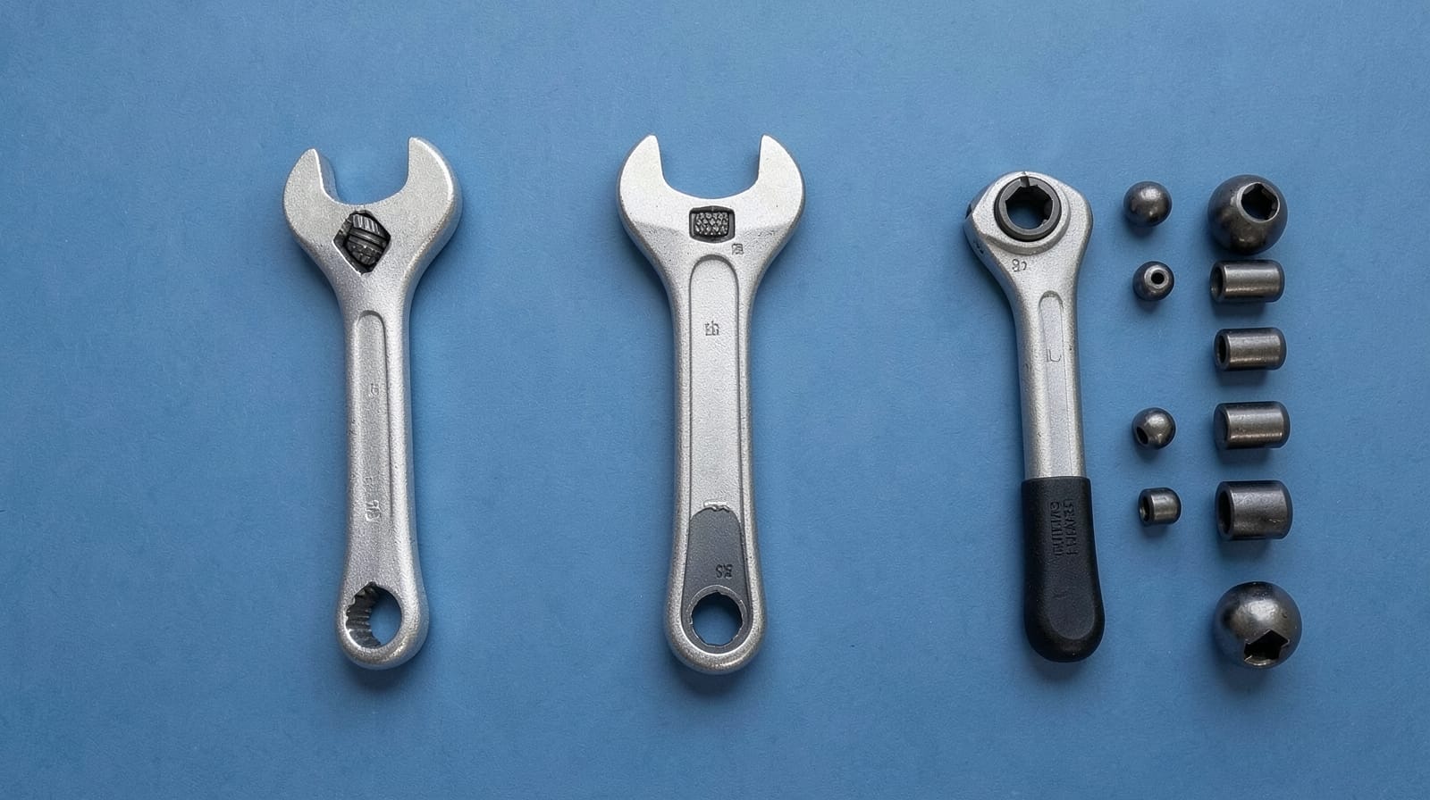 Three unbranded 1/2-inch torque wrenches and deep sockets on a slate-blue backdrop