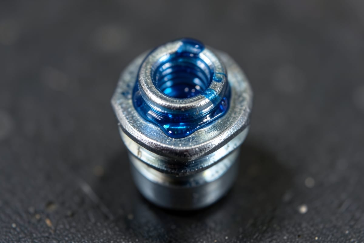 Blue threadlocker applied to the threads of a steel bolt
